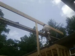 Carpenter setting a ridge beam over a new addition frame — Ice Dam Removal by Roofing Brothers in Richmondville