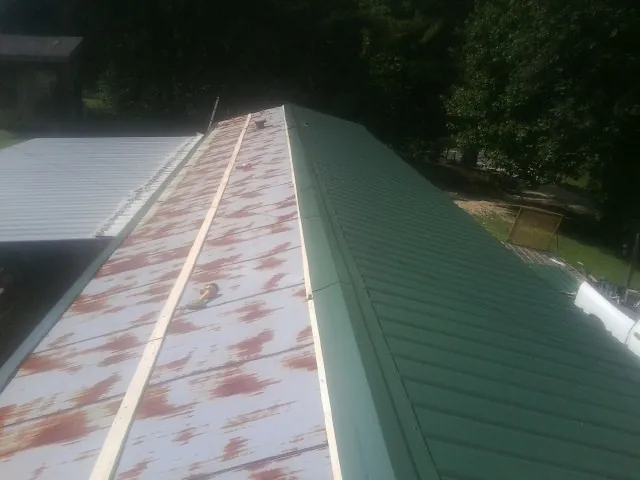 Old rusted panels beside newly installed green metal roofing — Wind Damage Roof Repair by Roofing Brothers in Richmondville