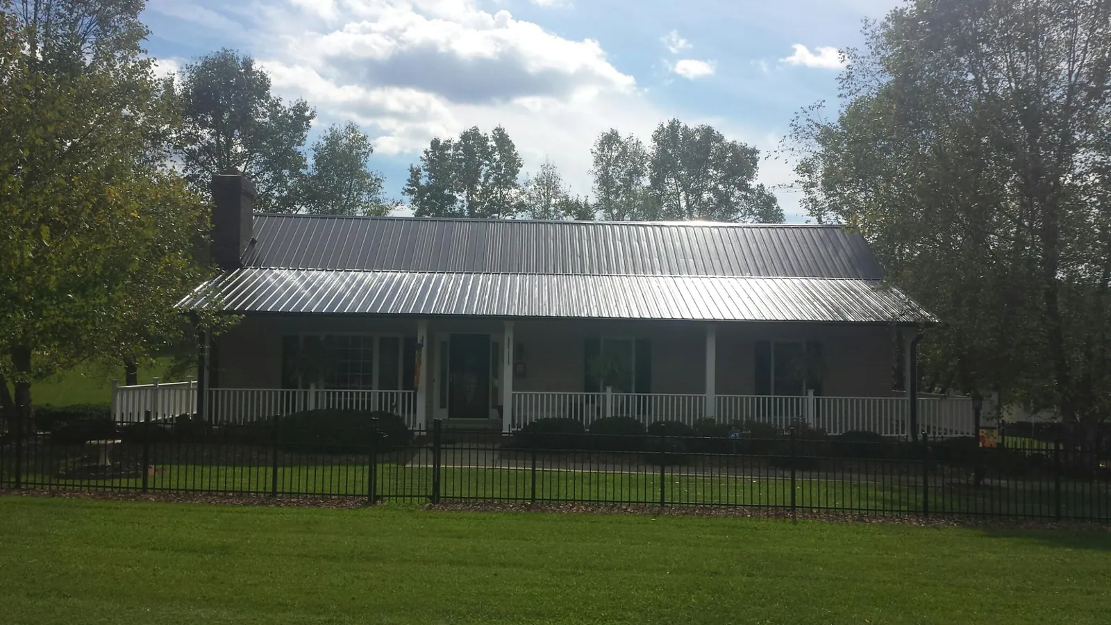 Gray metal roof on a brick ranch with a full width front porch — Gutter Guard Installation work by our crew in Richmondville