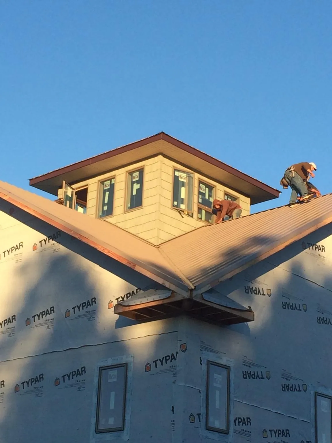 Roofers working around a rooftop cupola on a new metal roof at sunset — Roof Waterproofing in Richmondville by Roofing Brothers